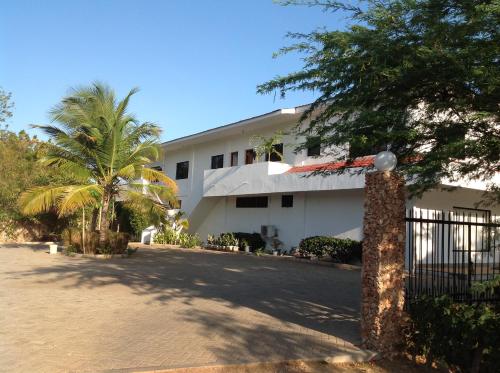 马林迪Ripasso Apartments的一座白色的建筑,有大门和棕榈树