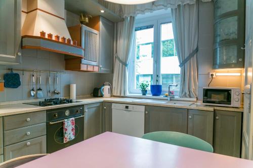 卢布尔雅那Tomas's apartment的厨房配有粉红色的桌子和一些窗户