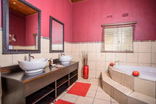 雾观阿邦甘旅舍的浴室设有2个水槽、浴缸和粉红色的墙壁。