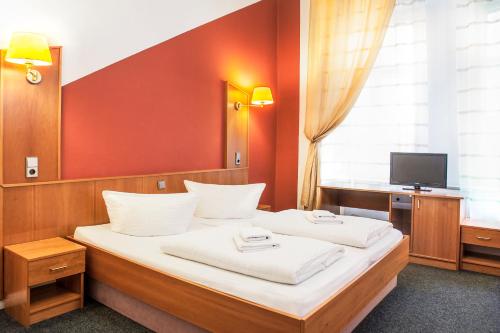 柏林潘森英瑟酒店的一间卧室配有一张带白色床单的床和一台电视。