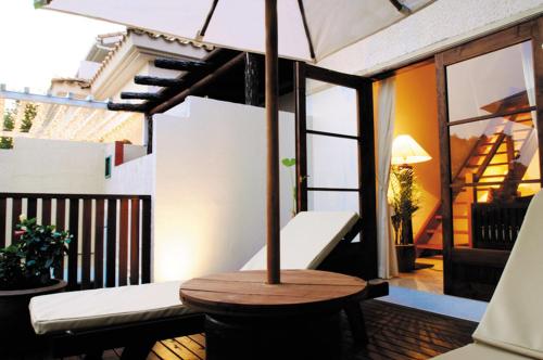 伊东伊豆高原考特拉哥酒店的阳台的天井配有桌子和遮阳伞。