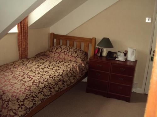普里茅斯Mountbatten Hotel的一间卧室配有一张床和一个带灯的梳妆台