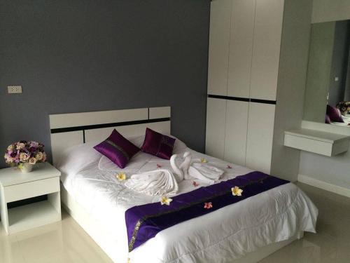 北芭堤雅Pandora House by Mike Group的一间卧室配有一张带紫色和白色床单及紫色枕头的床