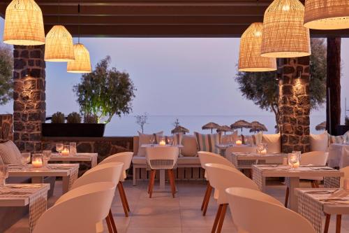 佩里萨水蓝色海滩酒店的餐厅配有白色的桌椅和灯光