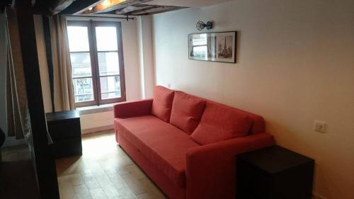 巴黎玛黑区之珠公寓的客厅里的一个红色沙发,带有窗户
