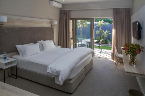 伊丽莎白港大洋湾旅馆的一间带一张白色大床的卧室和一个阳台