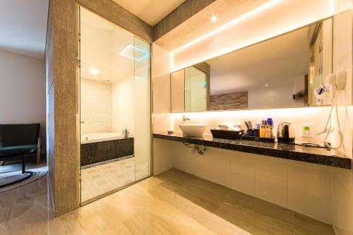 首尔SB汝矣岛精品酒店的浴室配有带水槽和浴缸的台面。