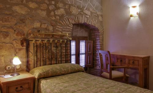 纳瓦斯-德尔马德罗尼奥Casa Rural La Chimenea的卧室配有1张床、1张桌子和1把椅子