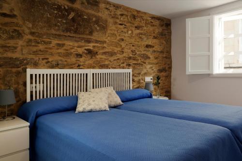 圣地亚哥－德孔波斯特拉Pensión Rua Nova的一间卧室配有一张蓝色的床和石墙