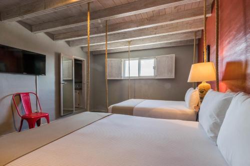 克雷塔罗Hotel Damiana Boutique的一间卧室配有一张床和一张红色椅子