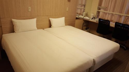 NishigoSmile Hotel Shirakawa的一张白色的大床,位于带两把椅子的房间