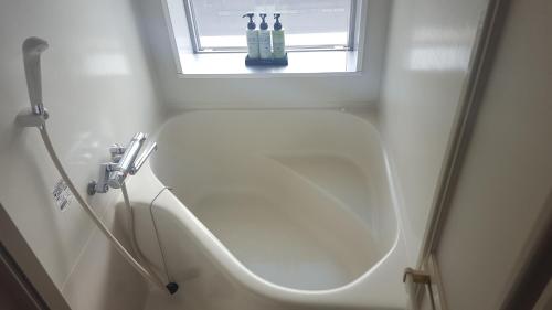 NishigoSmile Hotel Shirakawa的白色的浴室设有水槽和窗户。