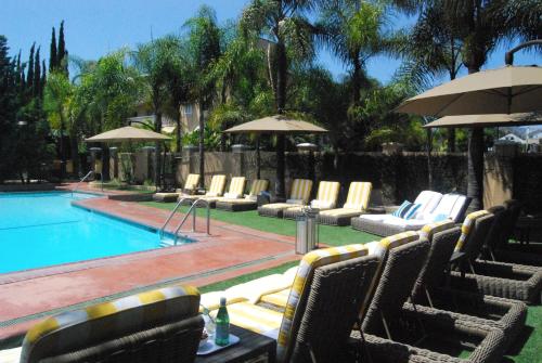 洛杉矶Hollywood Hotel的前方设有带椅子和遮阳伞的游泳池