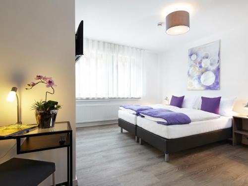 赫费尔霍夫Hotel Hegemann garni的一间卧室配有一张带紫色枕头的床和一张书桌