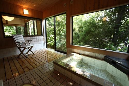 指宿市Onsensui Pool & Fufu Rotenburo no Hanareyado Yurian的门廊上配有浴缸和椅子的浴室