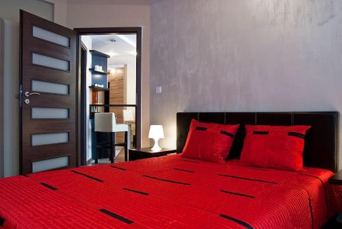 克雷尼察Apartament Perłowy的卧室内的红色床和红色枕头