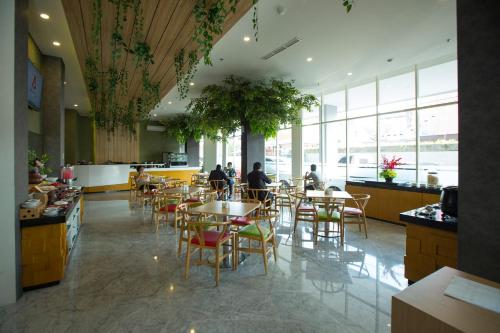 玛琅Ascent Hotel & Cafe Malang的一间设有桌椅的餐厅,以及坐在里面的人