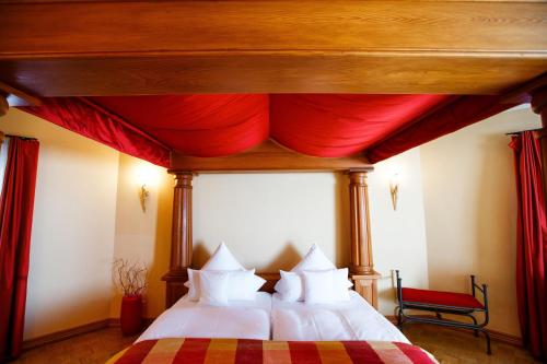 盖森海姆Burg & Gästehaus by Schwarzenstein的一间卧室配有一张带红色窗帘的床