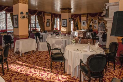 克莱恩 蒙塔纳高尔夫宫殿大酒店的用餐室配有桌椅和白色桌布