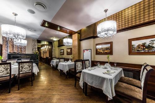 圣彼得堡斯特雅纳亚克伦威尔客旅馆的用餐室配有桌椅和吊灯。