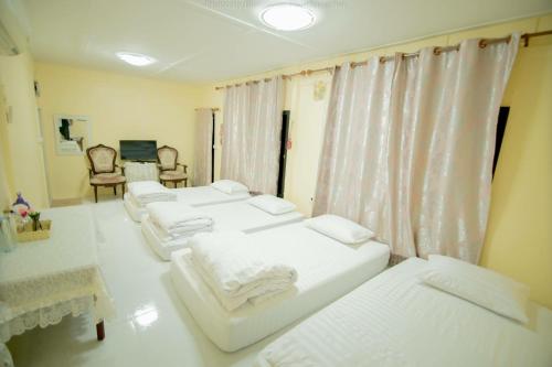 Phayayen巴耶延的言旅馆的客房设有4张白色的床和窗户。