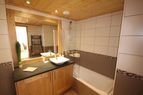 雷塞兹Les Saisies Bisanne的一间带水槽、浴缸和镜子的浴室