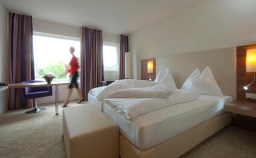 圣珀尔滕圣波罗城市酒店的一间酒店客房,配有一张床,还有人靠窗行走
