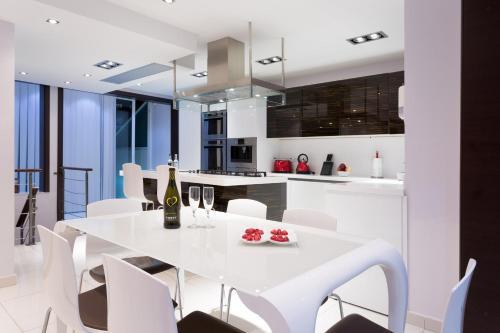 圣朱利安斯InStyle Aparthotel的厨房以及带白色桌椅的用餐室。