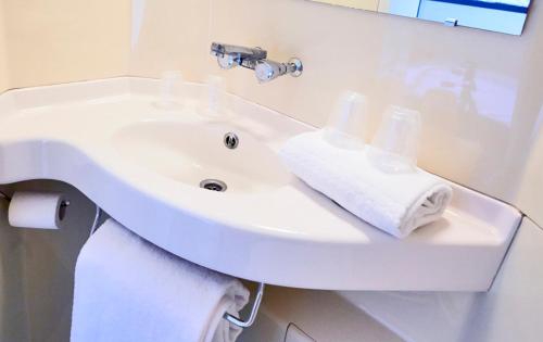 楠泰尔普瑞米尔巴黎西南特尔德芬斯经典酒店的白色浴室水槽和毛巾