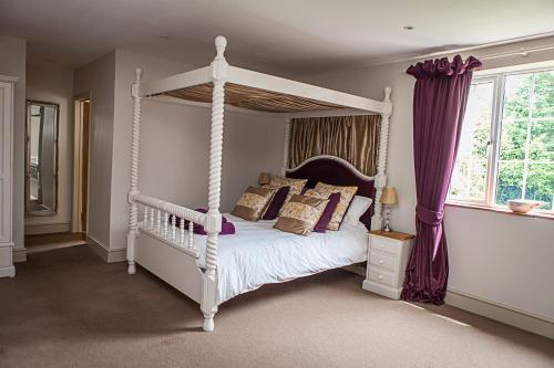 蒂弗顿Stoodleigh Court Coach House的卧室配有带枕头的白色天蓬床