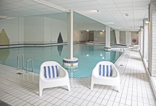 德布尔特迪斯弗莱彻酒店的游泳池前设有两把白色椅子