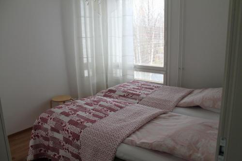 奥卢Apartment Nallisuites的一间卧室配有一张带毯子的床和窗户