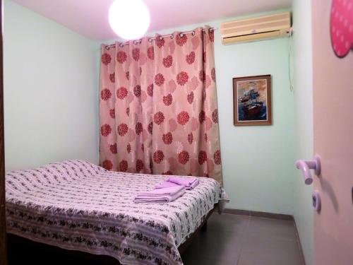 Atlit2 bedroom apartment in Atlit, Haifa district的一张小床,位于一个配有粉红色窗帘的房间