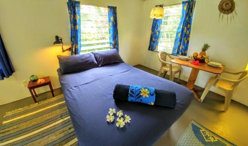 阿鲁坦加玛特里奇海滩小屋旅馆的一间卧室配有一张蓝色床单和鲜花的床。