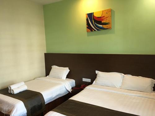 哥打京那巴鲁林达斯广场酒店的一间设有两张床的客房,墙上挂着一幅画