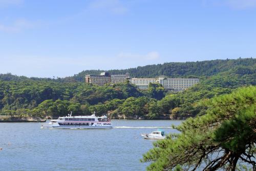 松岛町松岛大观庄度假酒店的两艘船在河上,有楼房