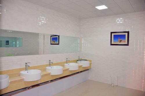 张掖张掖丝路行者青年旅舍的浴室设有3个水槽和一排镜子
