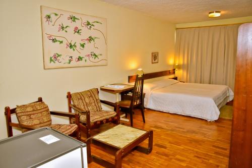 佩洛塔斯Hotel Estoril的酒店客房带一张床、一张桌子和椅子