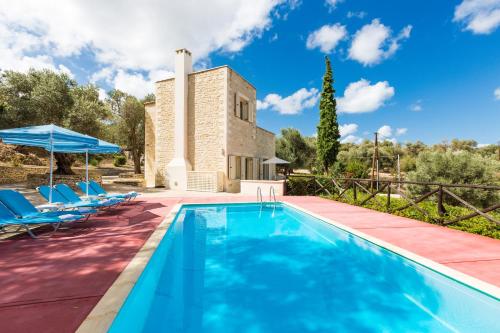马鲁拉斯Maroulas Villa Estate的一个带椅子的室外游泳池以及别墅