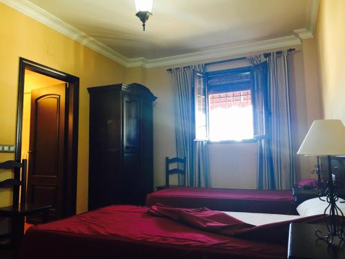 Huévar佩奇旅馆的一间卧室设有两张床和窗户。