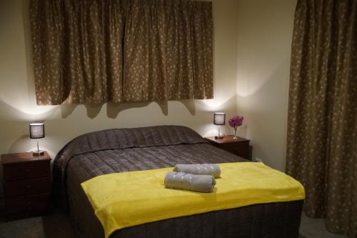 格雷默斯典雅风格度假屋的一间卧室配有一张带黄毯和两盏灯的床。