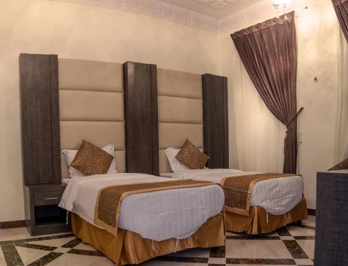 艾卜哈Rose Palace For Residential Units的配有两张床铺的酒店客房,设有大型床头板