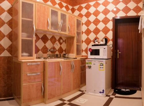 艾卜哈Rose Palace For Residential Units的一间带木制橱柜和冰箱的小厨房