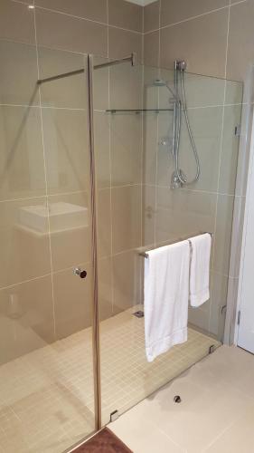 斯泰伦博斯Edelweiss Bed & Breakfast的玻璃门淋浴和白色毛巾