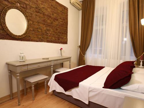伊斯坦布尔Green Star Taksim Hotel的一间卧室配有一张床、一张书桌和一面镜子