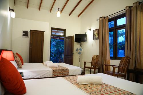 康提Kandy Moon Hills Hotel的酒店客房设有两张床和窗户。