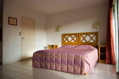 尼姆高尔夫公寓酒店的一间卧室配有一张带紫色床罩的床