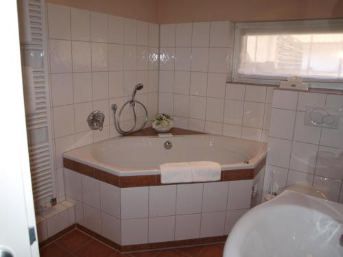 哈廷根维吉尔曼BIO兰德豪斯艾姆伍达恩塔尔酒店的白色瓷砖浴室设有浴缸和卫生间。