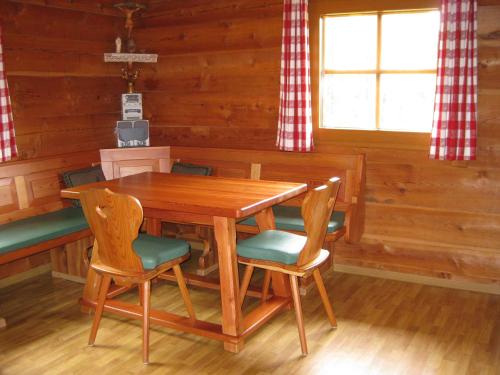 海利根布卢特Almhütte Adlerhorst的一间带木桌和椅子的用餐室