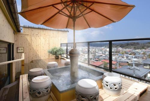 高山火沙卡库酒店的阳台的热水浴池和遮阳伞